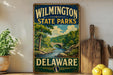 A vintage-style sign for Wilmington State Parks in Delaware, featuring a scenic landscape with a river, bridge, and trees.