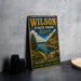 A vintage-style metal sign for Wilson State Park in Kansas, featuring a scenic landscape with a lake and mountains.