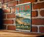 A vintage metal sign for Wilson State Park in Michigan, featuring a scenic landscape with a beach, mountains, and trees.