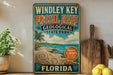 A vintage-style sign for Windley Key Fossil Reef State Park in Florida, featuring a tropical beach scene with palm trees and seashells.