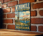 A vintage-style metal sign for the Windmill State Recreation Area in Nebraska, featuring a windmill and a scenic landscape.