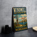 A vintage-style metal sign advertising the Windmill State Recreation Area in Nebraska, featuring a windmill, sailboat, and scenic landscape.