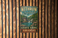 A vintage metal sign for Withrow Springs State Park in Arkansas, featuring a scenic illustration of a waterfall and a cabin.