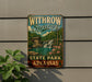 A vintage-style sign for Withrow Springs State Park in Arkansas, featuring a scenic image of a waterfall and a cabin.