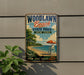A vintage-style metal sign for Woodlawn Beach State Park in New York, featuring a beach scene with a lifeguard chair, umbrella, and ocean waves.