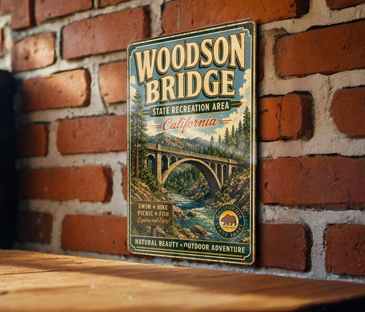 A vintage-style metal sign for the Woodson Bridge, a California state recreation area, is displayed on a brick wall.