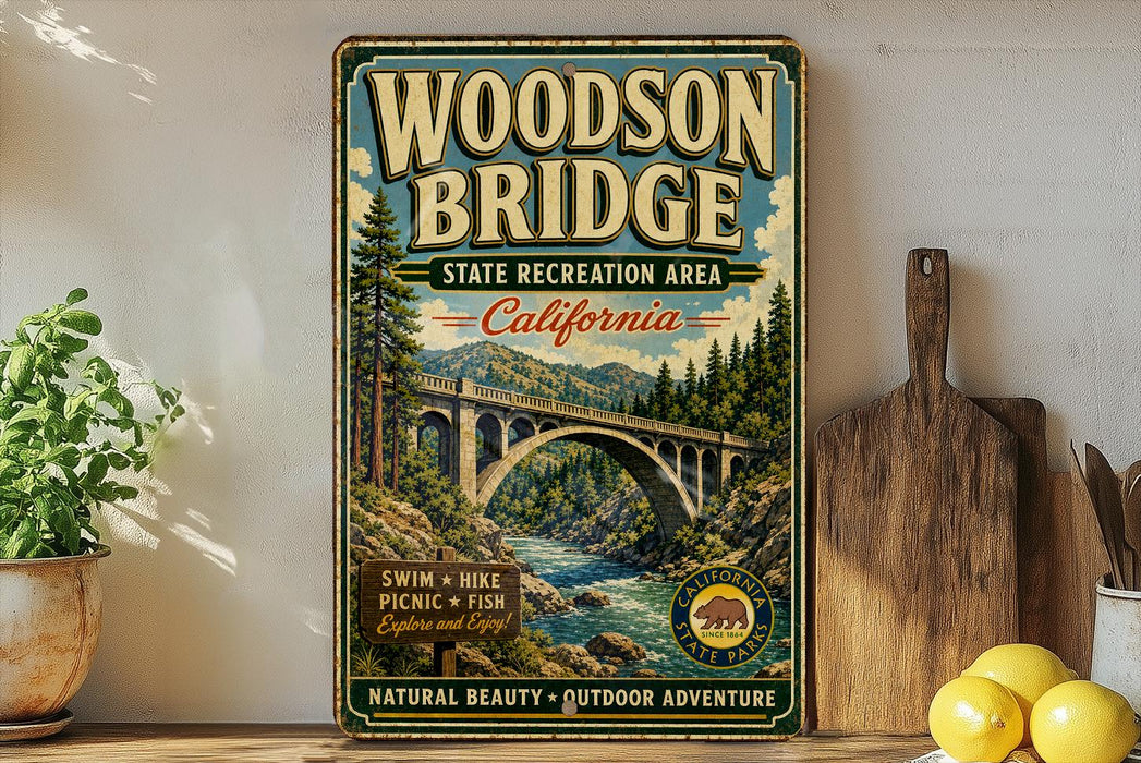 A vintage-style sign for the Woodson Bridge in California, featuring a scenic illustration of the bridge surrounded by trees and a river.