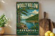 A vintage-style sign for Wolly Hollow State Park in Arkansas, featuring a scenic landscape with a river, trees, and a sailboat.