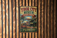 A vintage-style metal sign for Ybor City Museum, located in Florida, featuring a colorful illustration of a trolley car and palm trees.