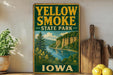 A vintage-style sign for Yellow Smoke State Park in Iowa, featuring a scenic landscape with a river and mountains.