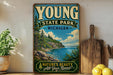 A vintage-style sign for Young State Park in Michigan, featuring a scenic landscape with a lake, mountains, and pine trees.