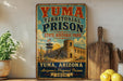 A vintage-style sign for Yuma Territorial Prison, featuring a castle and desert landscape, is displayed on a shelf next to a wooden cutting board and some lemons.