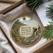 A decorative ornament with a scenic mountain landscape, featuring a winding path, a waterfall, and a bird perched on a branch.