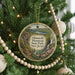 A round ornament hanging on a Christmas tree, featuring a scenic landscape with a waterfall and a path leading to a cliff.