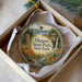 A decorative ornament in a box, featuring a scenic landscape with a waterfall, trees, and a deer.