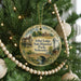 A round ornament hanging on a Christmas tree, featuring an illustration of a historic lodge and park in Nebraska.