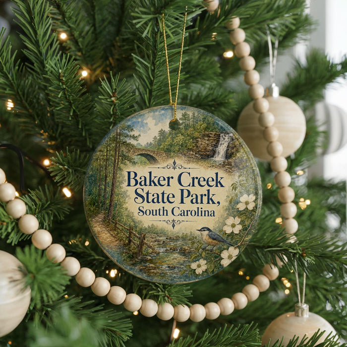 A round ornament hanging on a Christmas tree, featuring a scenic image of Baker Creek State Park in South Carolina.