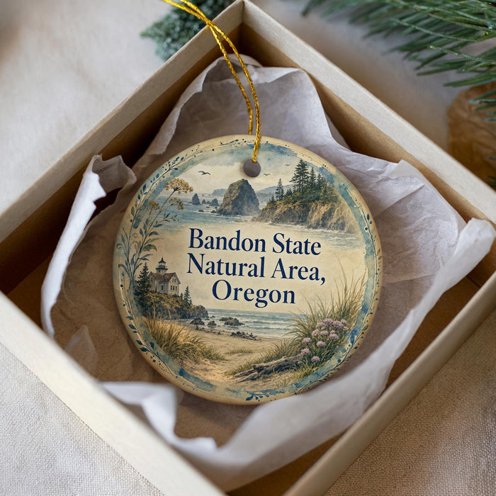 A decorative ornament in a box, featuring a scenic landscape with mountains, trees, and a lighthouse.