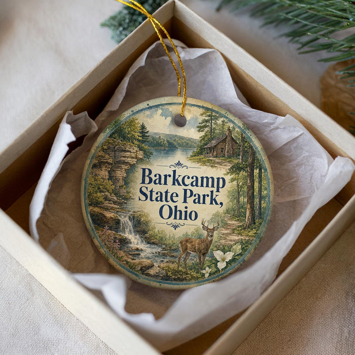 A circular ornament with a scenic landscape featuring a waterfall, forest, and deer, hanging from a string.