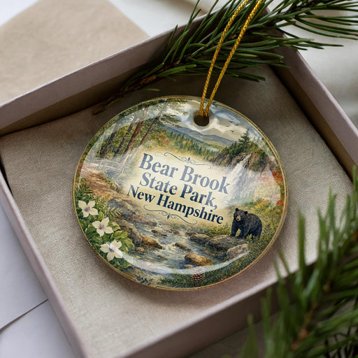 A decorative ornament featuring a bear and the text "Bear Brook State Park, New Hampshire" is displayed in a box with pine branches.