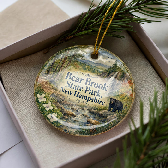 A decorative ornament featuring a bear and the text "Bear Brook State Park, New Hampshire" is displayed in a box with pine branches.