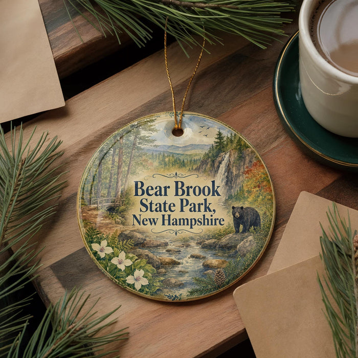 A round ornament with a painting of Bear Brook State Park, New Hampshire, featuring a bear, pine trees, and a stream.