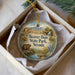A round ornament with a painting of a beaver in Beaver Dam State Park, Nevada, placed in a box with a white tissue paper lining.