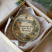 A decorative ornament in a box, featuring a scenic landscape with mountains, trees, and a beaver.