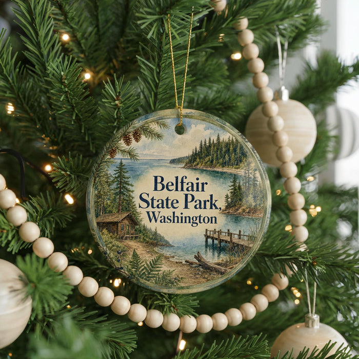 A round ornament hanging on a Christmas tree, featuring a scenic image of Belfair State Park in Washington.
