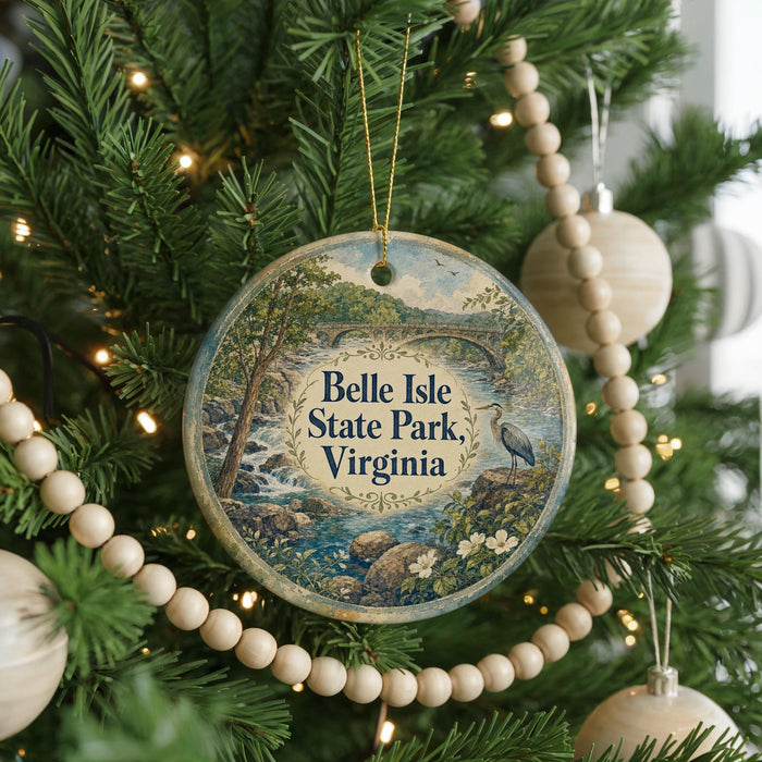 A round ornament hanging on a Christmas tree, featuring a scenic landscape with a river and trees.