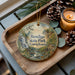 A decorative ornament featuring a scenic image of Bendigo State Park, Pennsylvania, with pine cones and a lit candle on a wooden tray.