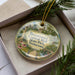 A decorative ornament in a box, featuring an illustration of the Capitol Mall in Tennessee.