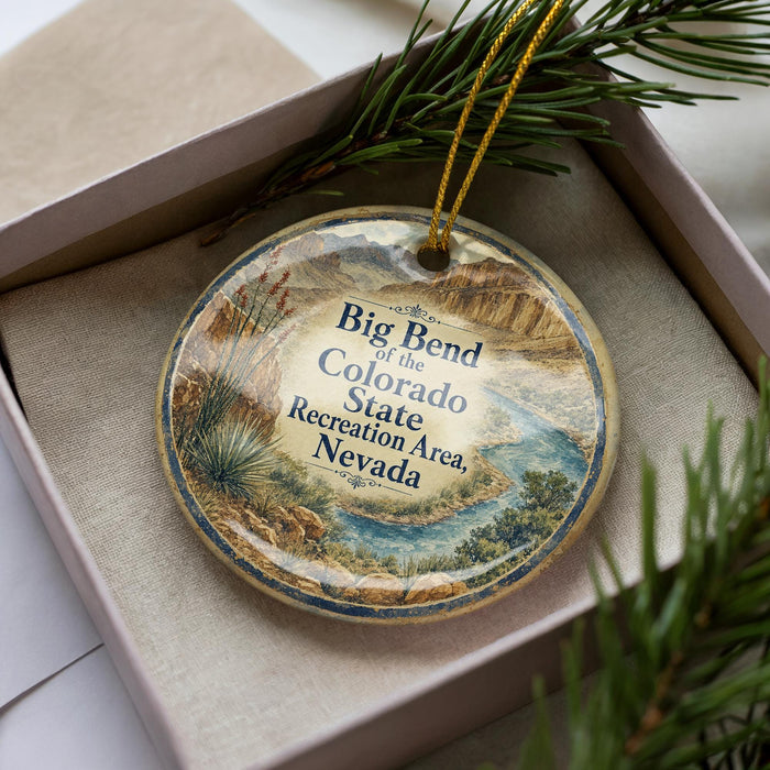 A decorative ornament in a box, featuring a scenic landscape of mountains, a river, and desert vegetation.