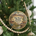 A round ornament hanging on a Christmas tree, featuring a desert landscape with mountains, a horse, and a windmill.