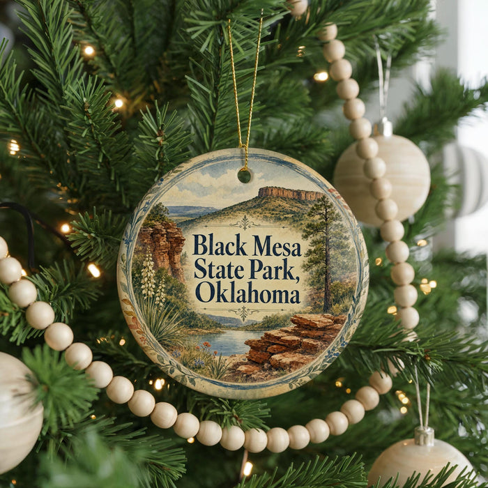 A Christmas tree decorated with ornaments, including a circular ornament with a scenic image of Black Mesa State Park, Oklahoma.