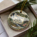 A decorative ornament in a box, featuring a scenic image of Blackwater Falls State Park in West Virginia.