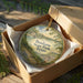 A circular ornament with a scenic landscape of Bonham State Park, Texas, displayed in a wooden box with a gold string.
