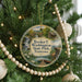 A round ornament hanging on a Christmas tree, featuring a scenic landscape with a waterfall, bridge, and boats.