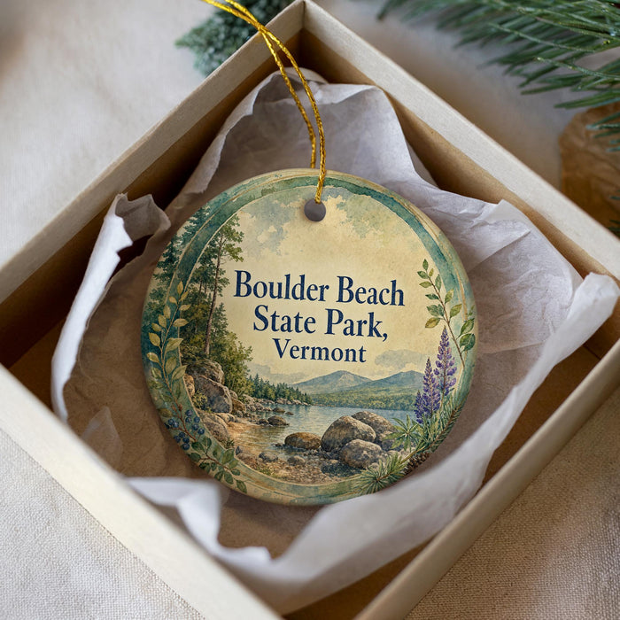 A round ornament with a scenic landscape of Boulder Beach State Park, Vermont, displayed in a box with a white tissue paper lining.