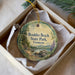A round ornament with a scenic landscape of Boulder Beach State Park, Vermont, displayed in a box with a white tissue paper lining.