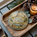 A wooden tray with a decorative ornament featuring a scenic landscape of Box Butte State Recreation Area, Nebraska, and pine cones.