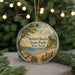 A round ornament with a scenic beach landscape and text, hanging on a string.
