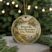 A round ornament with a scenic landscape of a river, a house, and birds, hanging on a string.