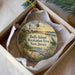 A decorative ornament in a box, featuring a lighthouse and a scenic landscape with a body of water and birds.