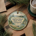 A decorative ornament with the text "Burton Island State Park, Vermont" on it, surrounded by pine branches and a cup of coffee on a wooden surface.