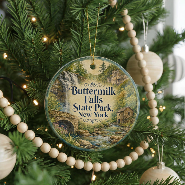 A round ornament hanging on a Christmas tree, featuring a scenic image of Butermilk Falls State Park in New York.