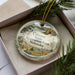 A decorative ornament in a box, featuring a scenic landscape with a deer and a river, along with the text "Calamus State Recreation Area, Nebraska".