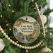 A round ornament hanging on a Christmas tree, featuring a scenic landscape with a waterfall and a bridge.
