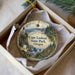 A decorative ornament in a box, featuring a lighthouse and a scenic landscape, with the text "Cape Lookout State Park, Oregon" printed on it.