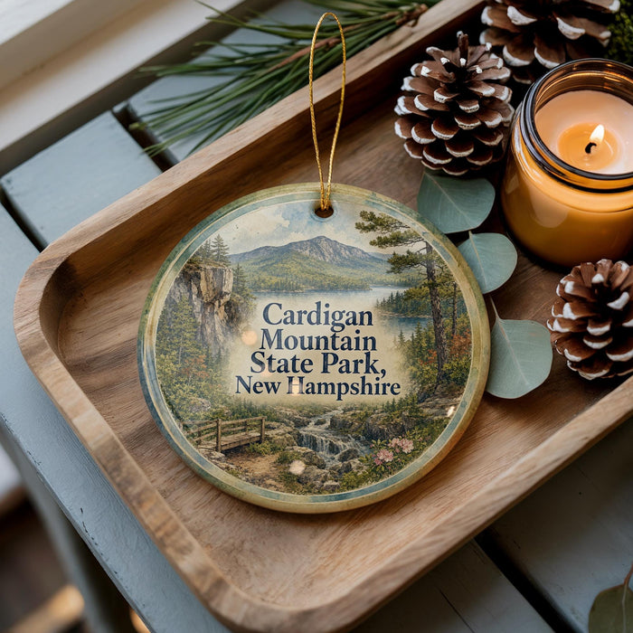 A wooden tray with a decorative ornament featuring a scenic mountain landscape, pine cones, and a lit candle.